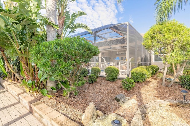 view of yard featuring glass enclosure, ceiling fan, and a patio area