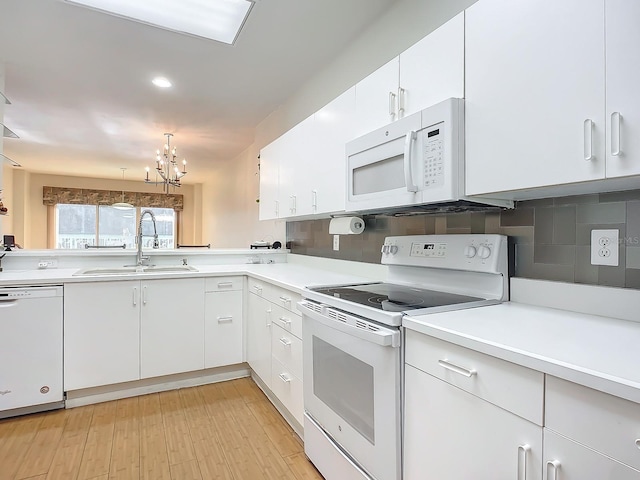 kitchen with an inviting chandelier, white appliances, sink, and white cabinets