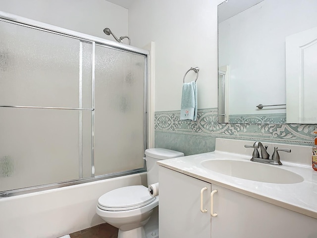 full bathroom featuring decorative backsplash, shower / bath combination with glass door, toilet, and vanity