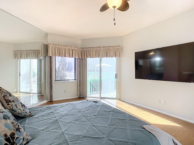 unfurnished bedroom with access to outside, multiple windows, wood-type flooring, and ceiling fan