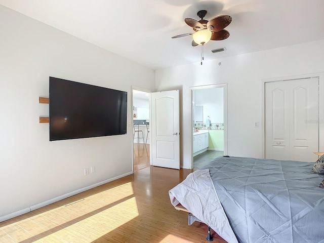 bedroom with hardwood / wood-style floors, ceiling fan, connected bathroom, and a closet