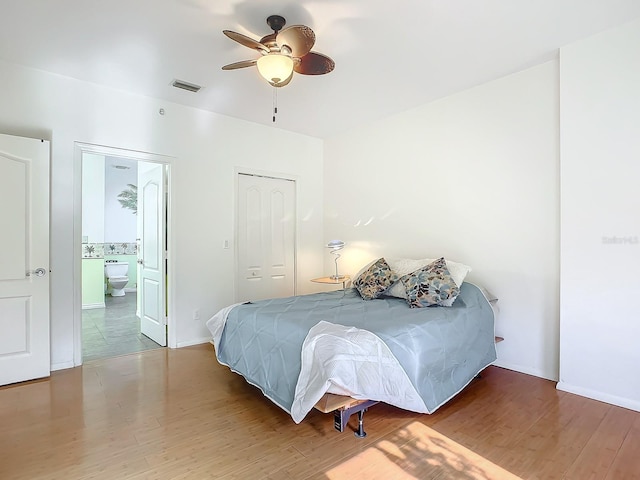 bedroom with ceiling fan, ensuite bathroom, wood-type flooring, and a closet