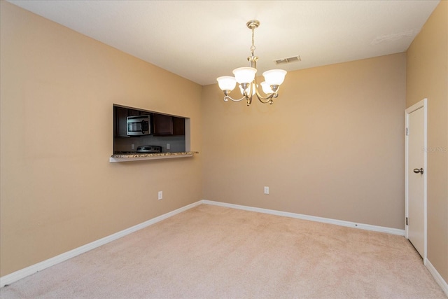 carpeted empty room with a notable chandelier