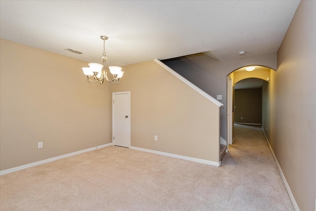 carpeted empty room with an inviting chandelier