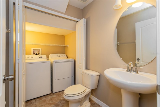 bathroom featuring sink, toilet, and washing machine and clothes dryer