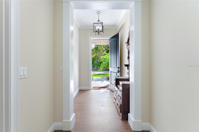 foyer entrance featuring ornamental molding, light wood-type flooring, and an inviting chandelier