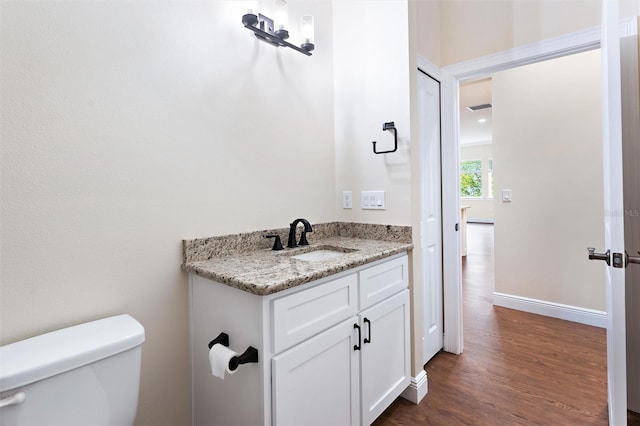 bathroom with toilet, vanity, and wood-type flooring