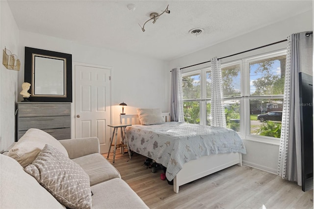 bedroom with light hardwood / wood-style flooring and a textured ceiling