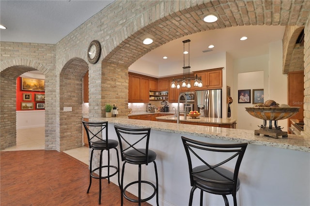 kitchen featuring kitchen peninsula, a breakfast bar area, light stone counters, and appliances with stainless steel finishes