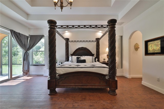 bedroom with dark hardwood / wood-style floors, a raised ceiling, and access to outside