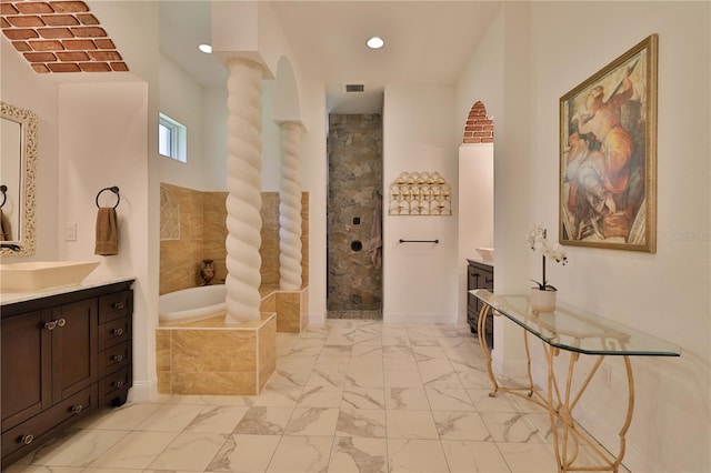 bathroom featuring decorative columns, vanity, and tiled bath