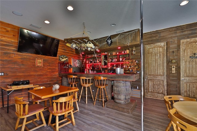 bar with dark hardwood / wood-style floors and wooden walls