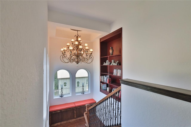 stairs with hardwood / wood-style flooring, a chandelier, and built in shelves