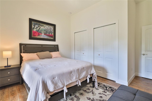 bedroom with light hardwood / wood-style floors and two closets