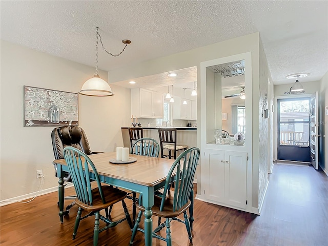 dining area featuring dark wood-type flooring, a textured ceiling, and ceiling fan