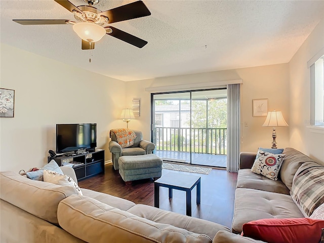 living room featuring dark wood-type flooring, ceiling fan, and a textured ceiling