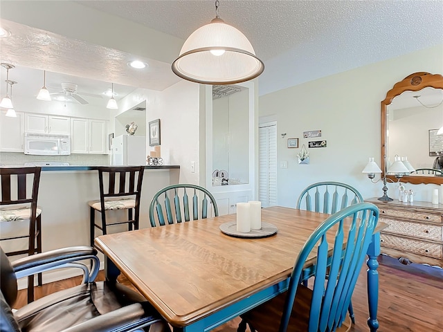 dining room featuring hardwood / wood-style flooring, a textured ceiling, and ceiling fan