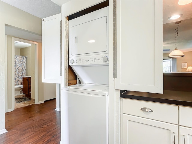 laundry area with dark hardwood / wood-style floors, a textured ceiling, and stacked washer / dryer