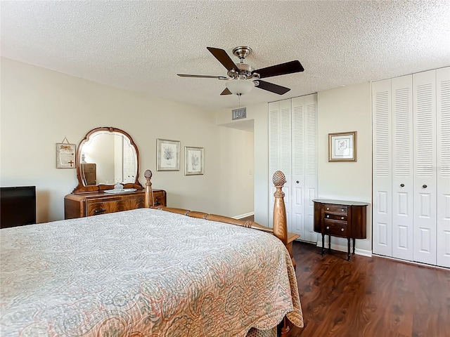 bedroom with dark wood-type flooring, a textured ceiling, ceiling fan, and multiple closets