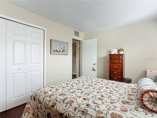 bedroom with dark hardwood / wood-style floors, a textured ceiling, and a closet