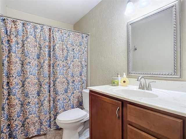 bathroom with toilet, vanity, and tile patterned flooring