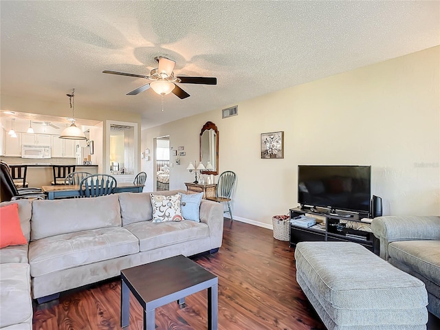 living room with ceiling fan, a textured ceiling, and dark hardwood / wood-style floors