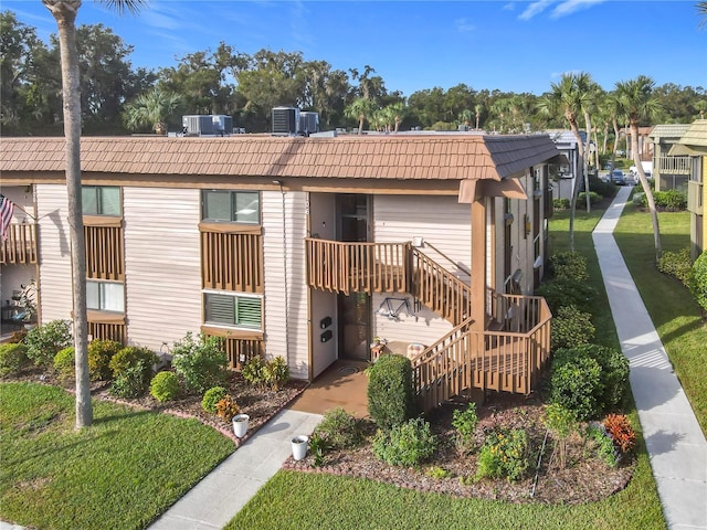 600 N Boundary Ave Unit 106D, Deland, FL 32720 - rear view of house featuring cooling unit, stairway, a yard, and mansard roof