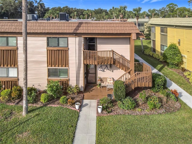 exterior space with a front lawn, central air condition unit, and a deck