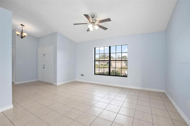 tiled spare room with ceiling fan with notable chandelier