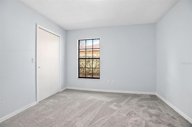 carpeted empty room featuring a textured ceiling