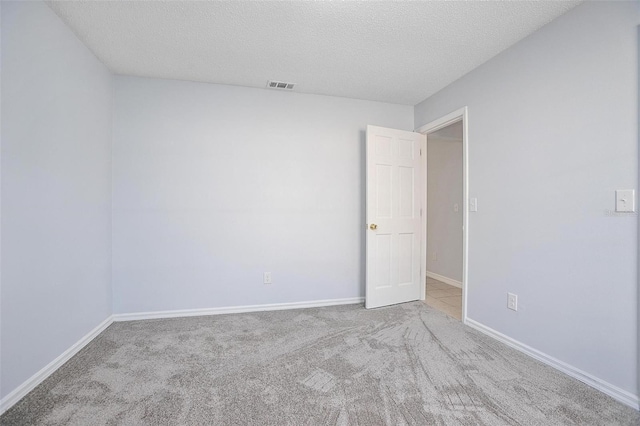 empty room featuring a textured ceiling and light carpet