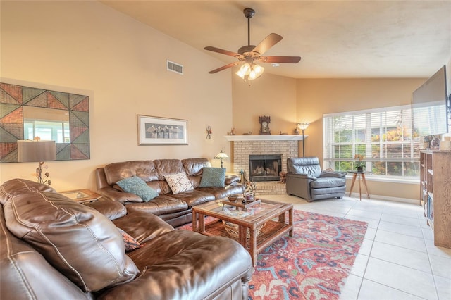 tiled living room with a brick fireplace, ceiling fan, and high vaulted ceiling