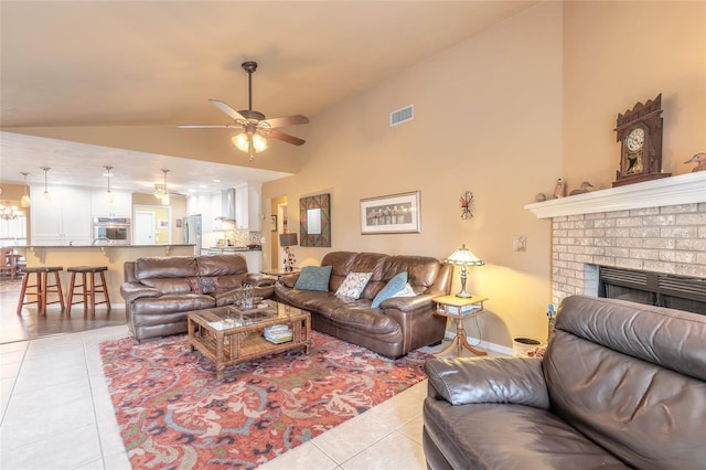 tiled living room featuring lofted ceiling, ceiling fan, and a fireplace