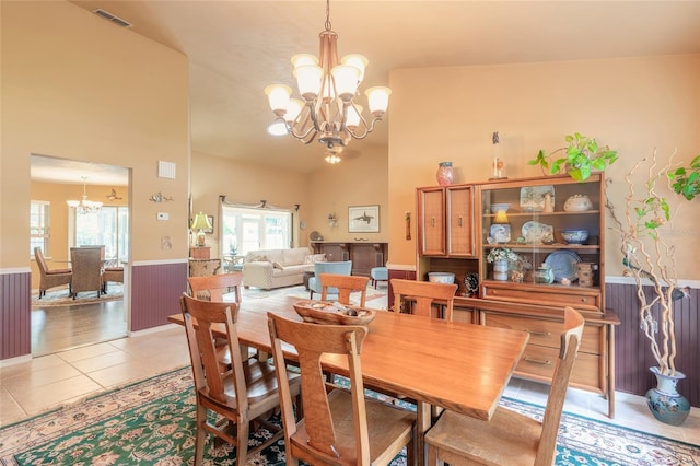 dining area with high vaulted ceiling, light hardwood / wood-style floors, and an inviting chandelier