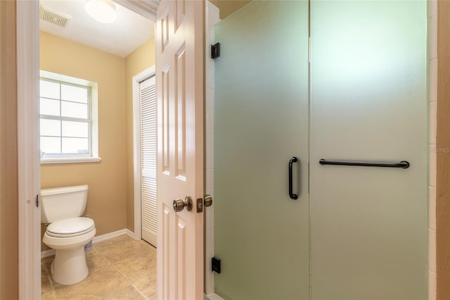 bathroom with a shower with door, tile patterned flooring, and toilet