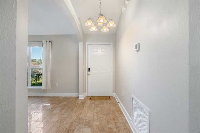 entrance foyer featuring light hardwood / wood-style floors, an inviting chandelier, and vaulted ceiling