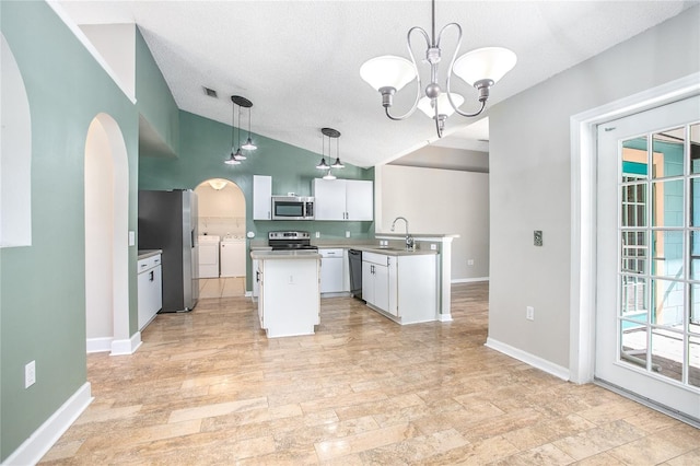 kitchen featuring stainless steel appliances, washing machine and dryer, a chandelier, pendant lighting, and white cabinets