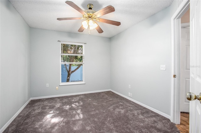 empty room featuring ceiling fan, dark carpet, and a textured ceiling