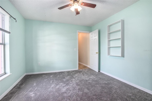 empty room with carpet flooring, ceiling fan, and a textured ceiling