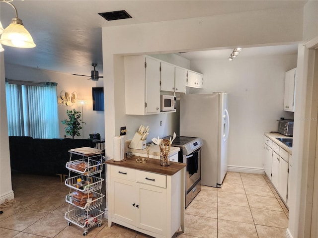 kitchen featuring white cabinets, appliances with stainless steel finishes, light tile patterned floors, and sink