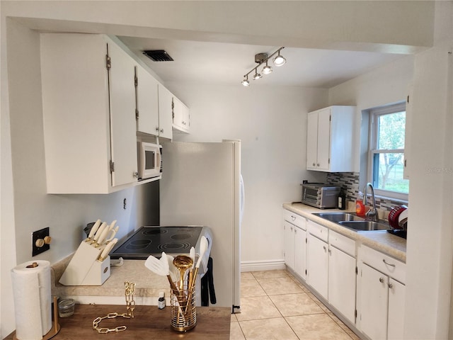 kitchen with white cabinetry, sink, light tile patterned floors, and range