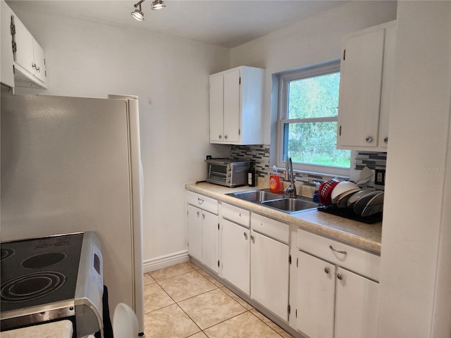 kitchen with white cabinets, stove, sink, and tasteful backsplash