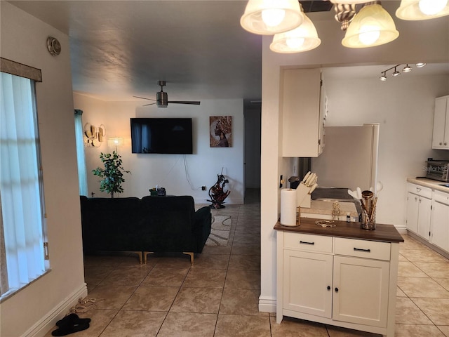 kitchen with tile patterned flooring, decorative light fixtures, white cabinetry, and stainless steel refrigerator