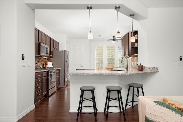 kitchen with ceiling fan, sink, dark wood-type flooring, kitchen peninsula, and appliances with stainless steel finishes