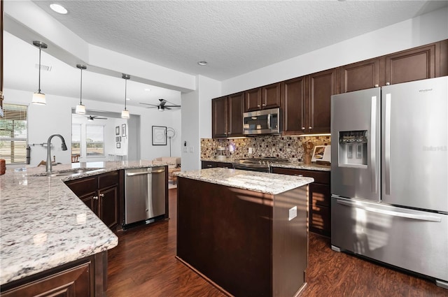 kitchen featuring a textured ceiling, dark hardwood / wood-style floors, hanging light fixtures, and appliances with stainless steel finishes