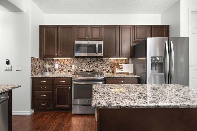 kitchen featuring dark brown cabinetry, stainless steel appliances, and dark hardwood / wood-style floors