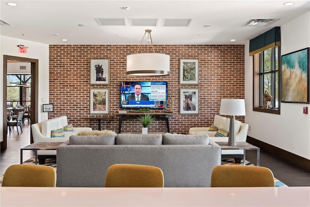 living room with hardwood / wood-style floors and brick wall