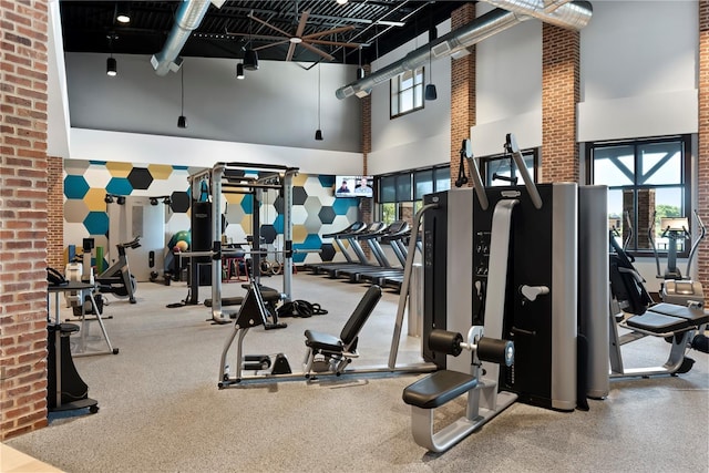 workout area featuring a high ceiling and brick wall