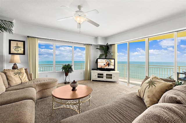 living room featuring ceiling fan, ornamental molding, and carpet