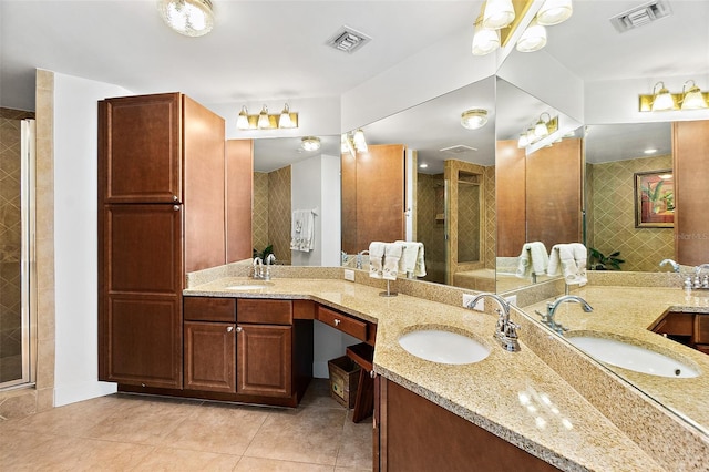 bathroom with a shower with door, vanity, and tile patterned floors